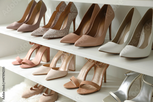 Different stylish women's shoes on shelving unit photo