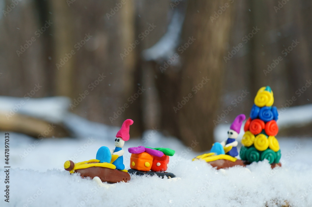 Christmas figures on a snowmobile made of plasticine carry a Christmas tree and gifts. The action takes place in a snowy forest.