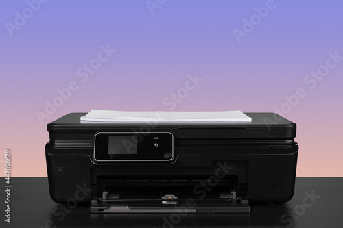 Home laser printer on desk against purple background