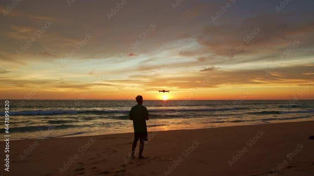 stunning colorful clouds in yellow sky at sunset..A man flying drone in stunning colorful yellow sky at sunset..Tourists piloting drones to take pictures of beautiful sunset. stunning colorful clouds in yellow sky at sunset..A man flying drone in stunning colorful yellow sky at sunset..Tourists piloting drones to take pictures of beautiful sunset.