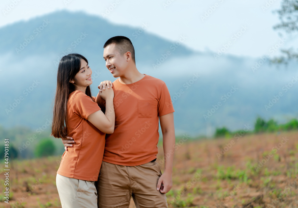 Portrait An Asian couple in identical brown shirts cuddling happily against a foggy and mountain backdrop. Portrait An Asian couple in identical brown shirts cuddling happily against a foggy and mountain backdrop.