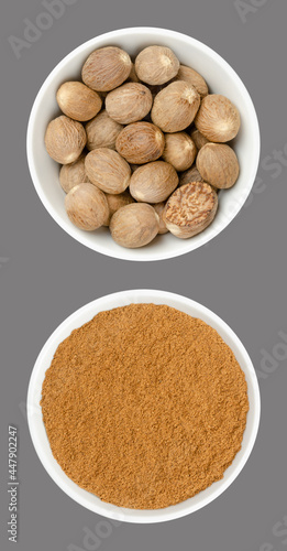 Whole nutmegs and nutmeg powder, in white bowls, on gray background. Fragrant or true nutmeg, dried seeds of Myristica fragrans, a spice, also used in traditional medicine. Close-up from above, photo.