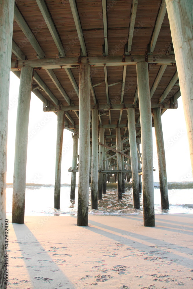 Underneath large wooden pier on beach over ocean