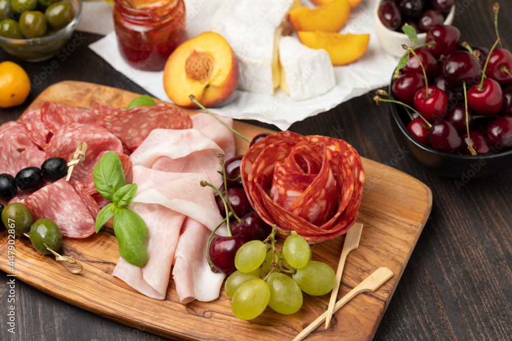 Salami, prosciutto ham, olives, cherry, grape. food snacks for an aperitif, a picnic, for a festive dinner or a party. Salami, prosciutto ham, olives, cherry, grape. food snacks for an aperitif, a picnic, for a festive dinner or a party.