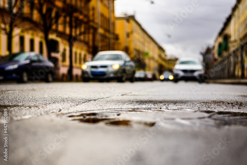 Rainy day in the big city, the headlights of the approaching cars. Close up view of a hatch at the level of the asphalt