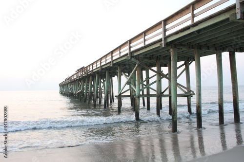 Beach scene with wooden pier over ocean at sunrise © Brian