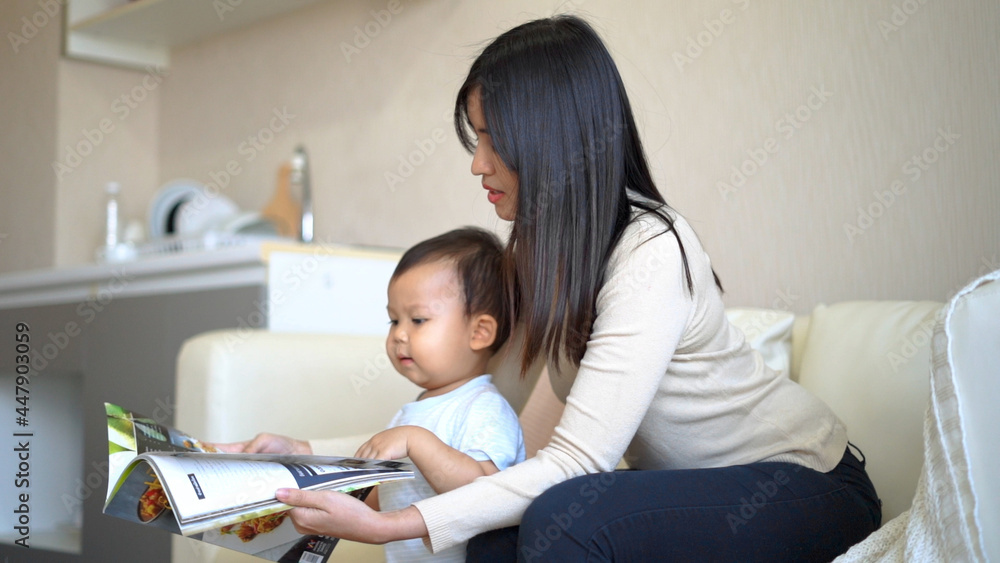 Young mother and little boy child reading book sitting on floor near sofa. Young mother and little boy child reading book sitting on floor near sofa.