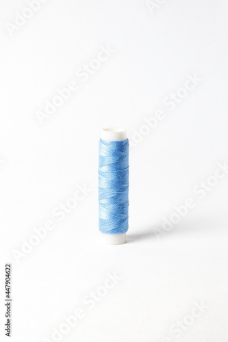 A small bobbin with blue threads on a white background