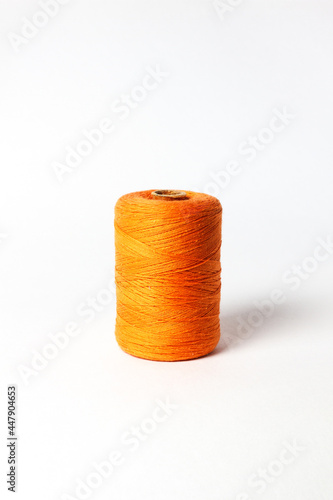 A spool of orange thread. White background.