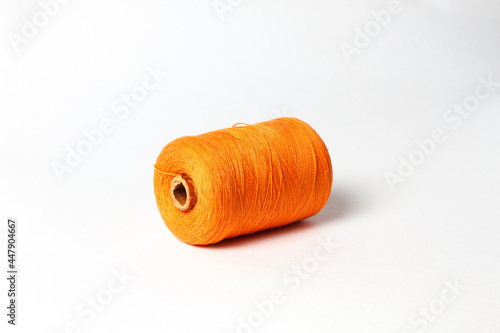 A spool of orange thread. White background.