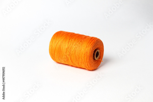 A spool of orange thread. White background.