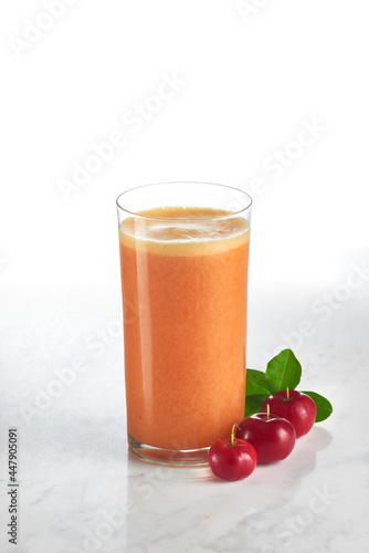 Copo com suco de acerola e laranja com frutos de acerola decorando a base photo