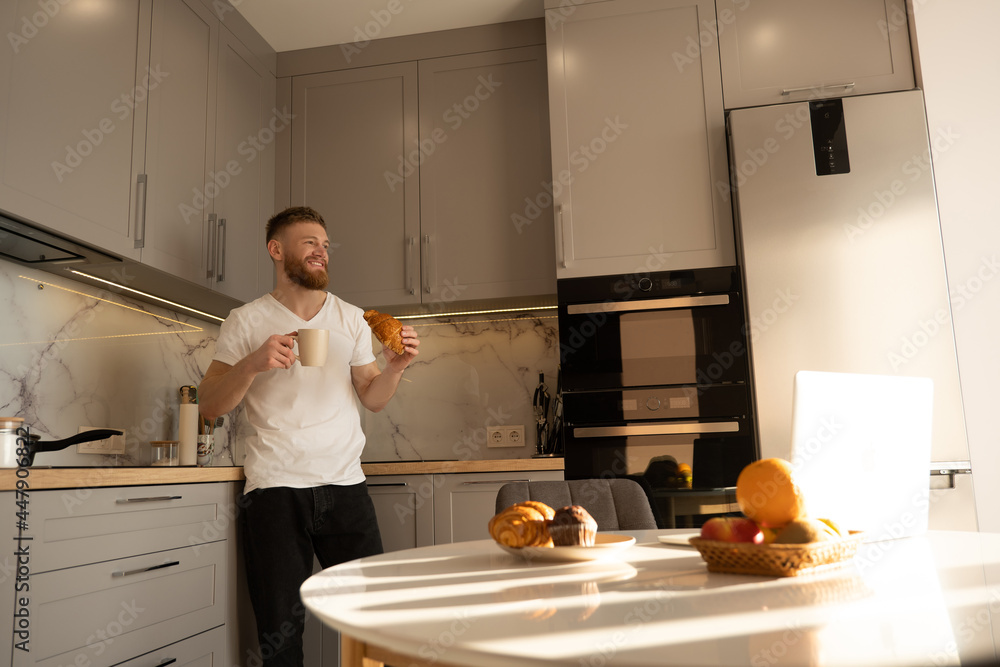 Man eating croissant and drinking tea on breakfast Man eating croissant and drinking tea on breakfast