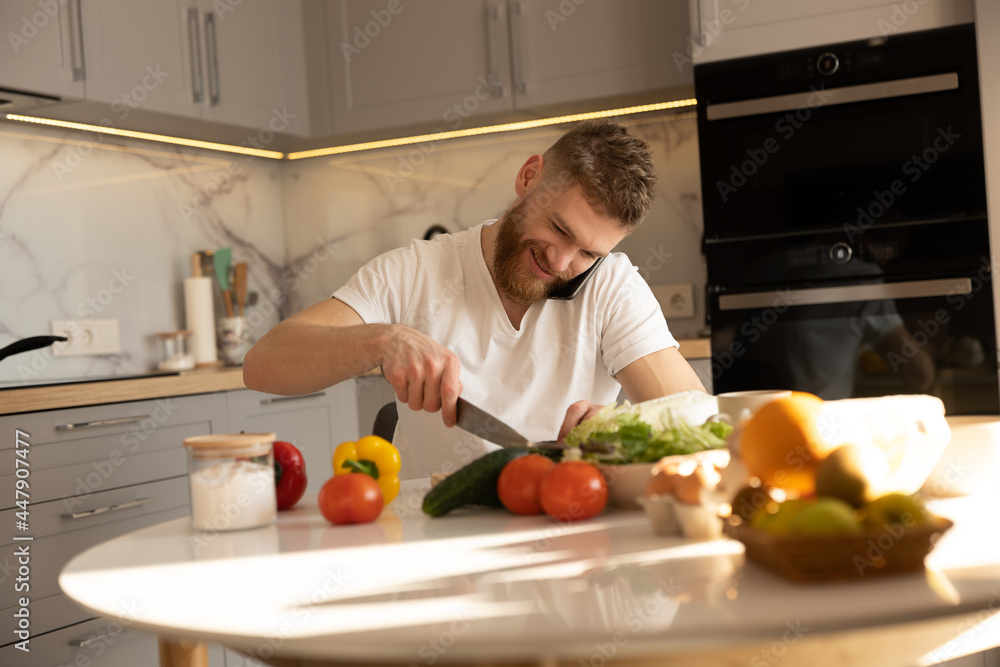 Man talking on mobile phone and cutting cucumber