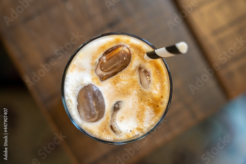 Top down view of a ice latte coffee with a straw on a wooden table