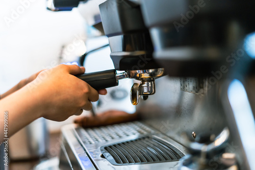 Close-up hand of barista plug the portafilter into coffee machine to make espresso