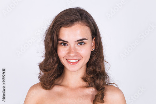 Young beautiful natural soft clean skin woman with freckles light makeup on white background with bare shoulders