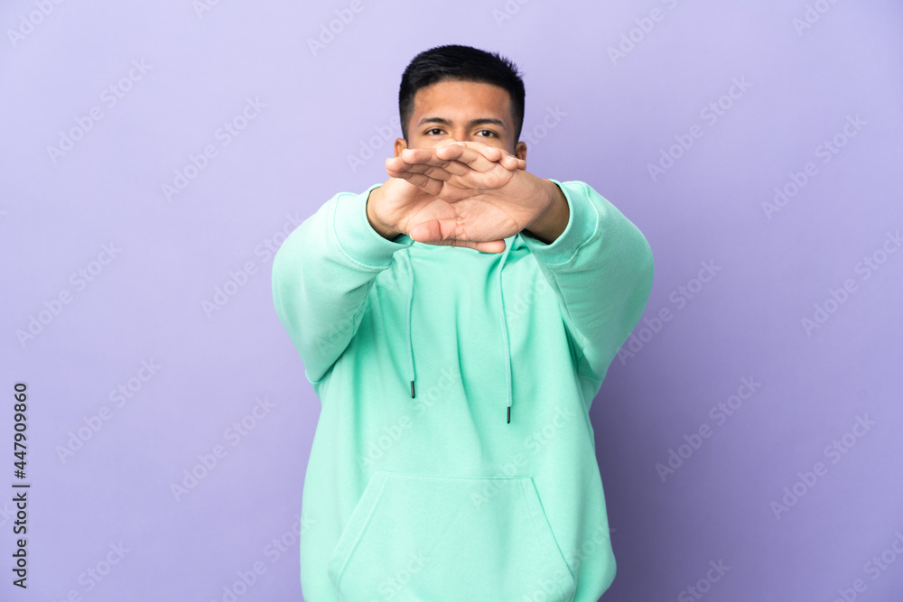 Young Ecuadorian man isolated on purple background making stop gesture with her hand to stop an act Young Ecuadorian man isolated on purple background making stop gesture with her hand to stop an act