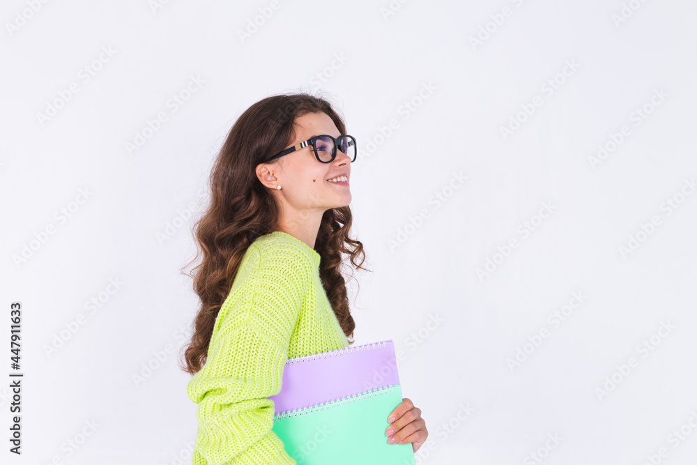 Young beautiful woman with freckles light makeup in sweater on white background eyes glasses and notebooks cheerful happy smile Young beautiful woman with freckles light makeup in sweater on white background eyes glasses and notebooks cheerful happy smile