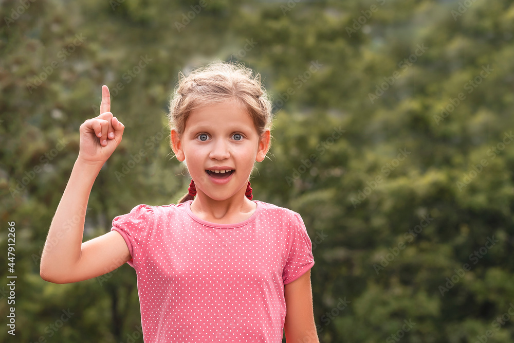 The little girl raised her index finger. Portrait of a child on a green background The little girl raised her index finger. Portrait of a child on a green background