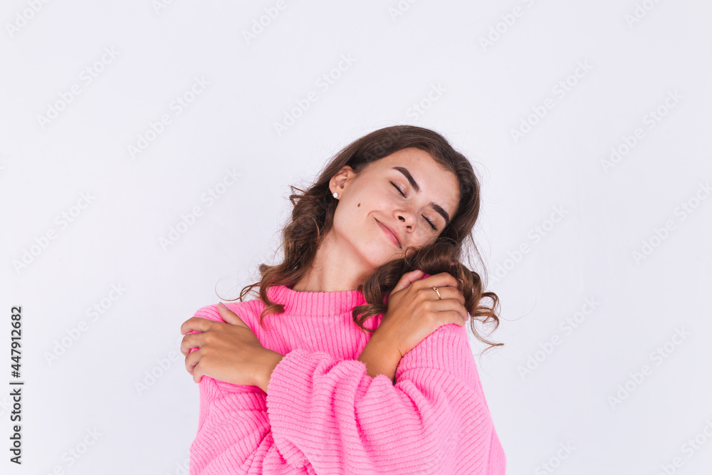 Young beautiful woman with freckles light makeup in sweater on white background hugging herself, self care and love concept Young beautiful woman with freckles light makeup in sweater on white background hugging herself, self care and love concept