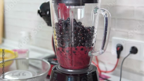 Black currant, preparation of a berry cocktail. Berries are ground in a blender. Slow motion
