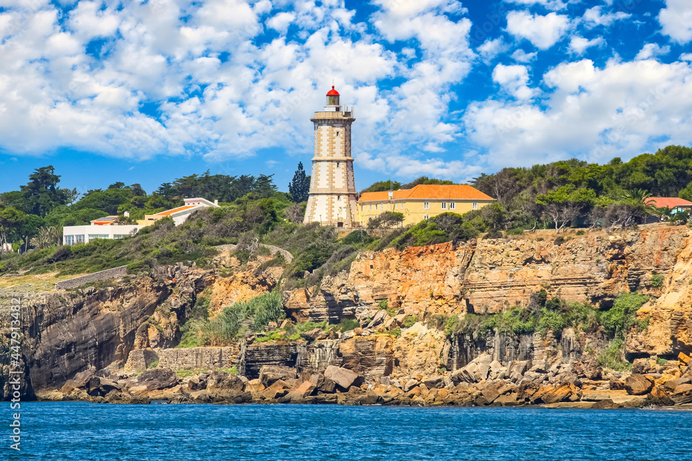 Lighthouse on a rock cliff and blue sky with clouds. Lisbon Portugal.