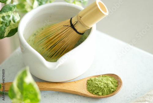 Mixing matcha with wooden spoon and chasen whisk in chawan bowl.