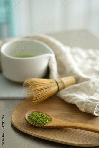 Mixing matcha with wooden spoon and chasen whisk in chawan bowl.