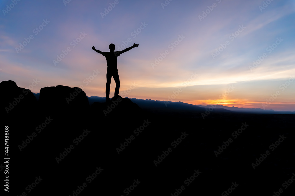 Silhouette of a winner man standing on a mountain. The concept of sports and active life. 