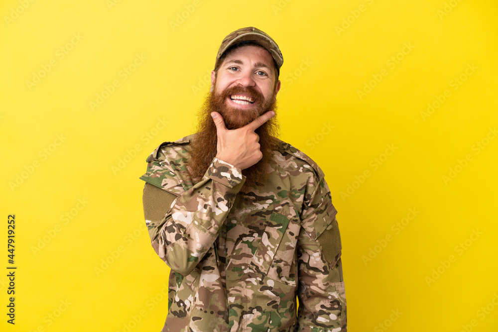 Military Redhead man over isolated on yellow background smiling Military Redhead man over isolated on yellow background smiling