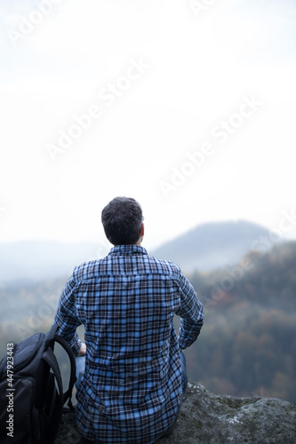 Mann sitzt auf den Berg und blickt in die Ferne