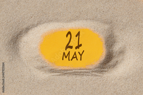 May 21. 21th day of the month, calendar date. Hole in sand. Yellow background is visible through hole. Spring month, day of the year concept photo