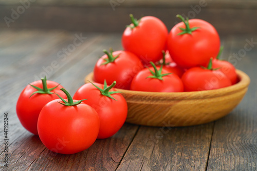 fresh red tomatoes in a wooden bowl on a table.