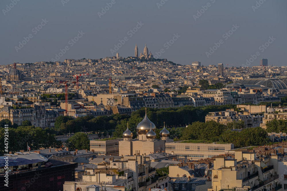 Paris, France - 07 22 2021: Eiffel Tower: View of Cathedral of the Holy Trinity and Montmartre district at sunset in Paris