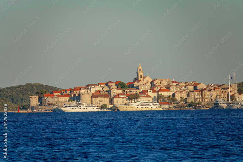 AERIAL: Scenic shot of a ferry and a yacht departing island of Korcula at sunset