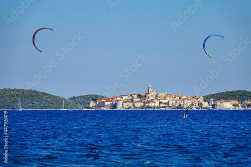 Athletic male tourist kitesurfs near beautiful Korcula island on a sunny day.