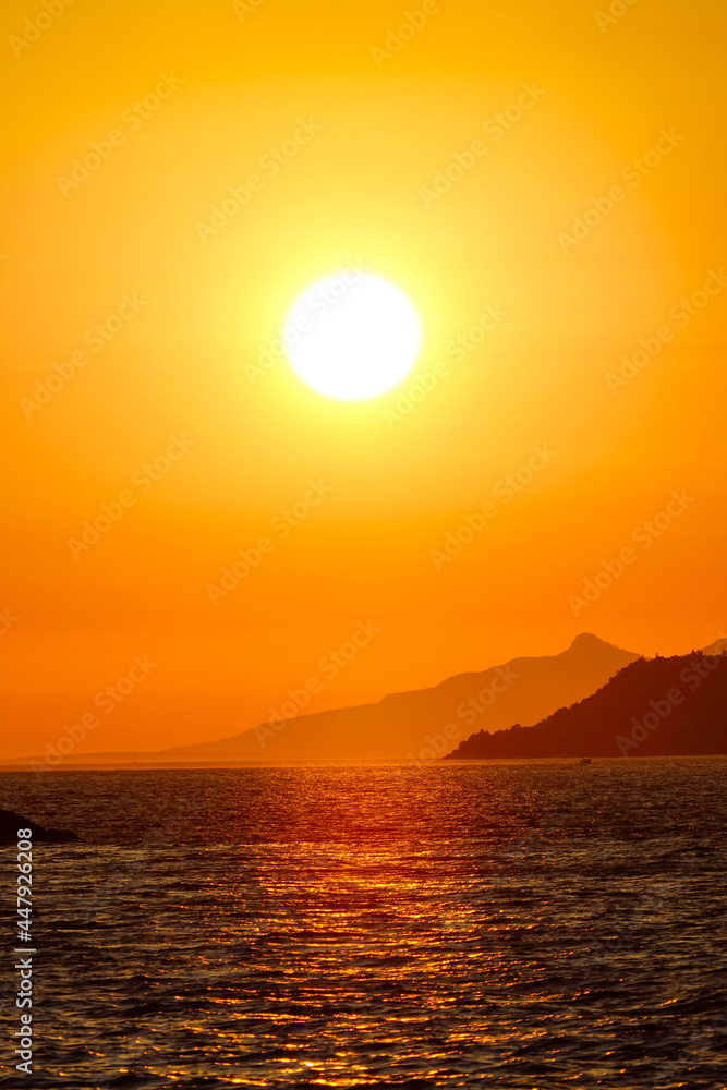 VERTICAL: Vista of setting sun illuminating the Mediterranean sea in Croatia