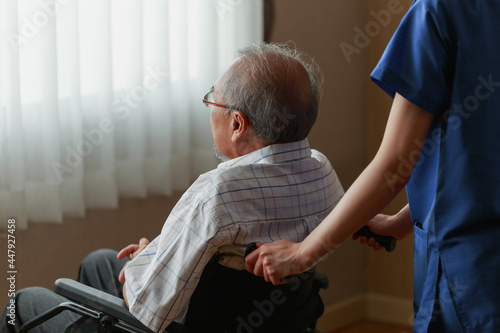 Young Asian woman nurse explaining information to elderly man patient in wheelchair with friendly smiley face in the hospital. Young Assistance with old people in the elderly care place