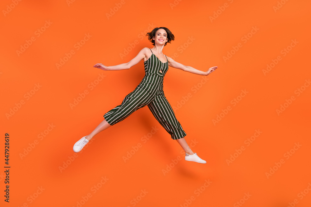 Full size profile side photo of young excited girl happy positive smile jumper split sporty isolated over orange color background