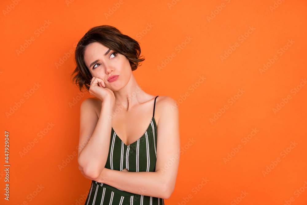 © deagreez - Photo of young girl hand touch cheek bored annoyed think idea plan look empty space isolated over orange color background