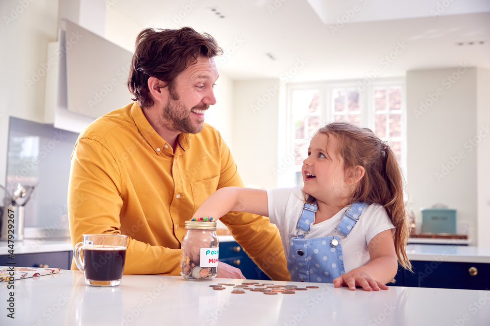 Father And Daughter Counting Pocket Money In Jar On Kitchen Counter Father And Daughter Counting Pocket Money In Jar On Kitchen Counter
