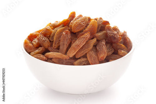 Close-up of golden long size raisins (dry grapes )in a white ceramic bowl over white background.