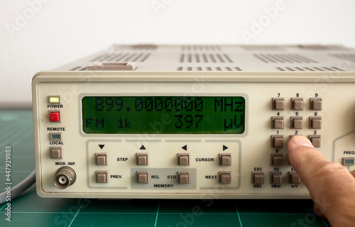 Man's hand pressing the buttons of a frequency counter