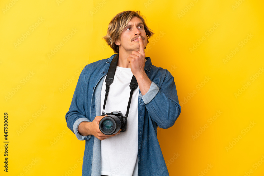 Young photographer man isolated on yellow background having doubts while looking up Young photographer man isolated on yellow background having doubts while looking up