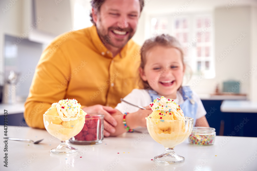 Father And Daughter In Kitchen Decorating Ice Cream Dessert With Cream And Sprinkles