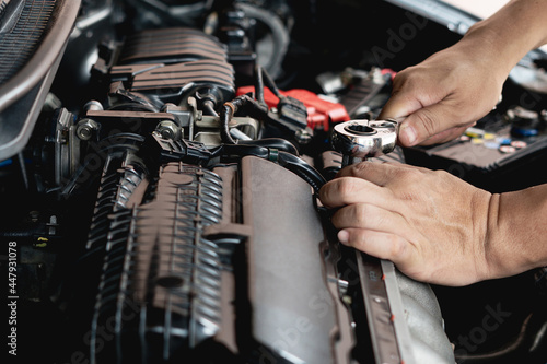 Closeup spanner in hand male mechanic repairs car in garage. Car maintenance and auto service garage concept