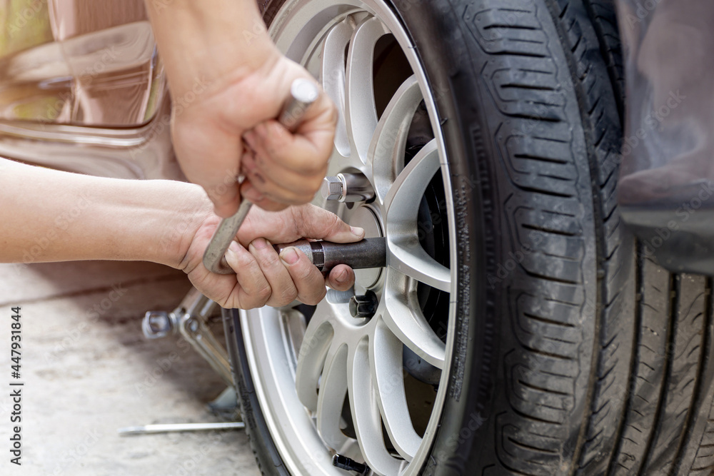 Home service car concept : A man repairing action lock bolt of car wheel for check the car's drive system basic maintenance that can be made by yourself Home service car concept : A man repairing action lock bolt of car wheel for check the car's drive system basic maintenance that can be made by yourself