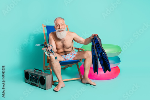 Full length body size view of attractive cheery man preparing diving tools isolated over teal turquoise color background