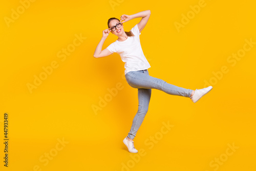 Full size profile side photo of young cheerful girl happy positive smile go walk hans touch eyeglasses isolated over yellow color background